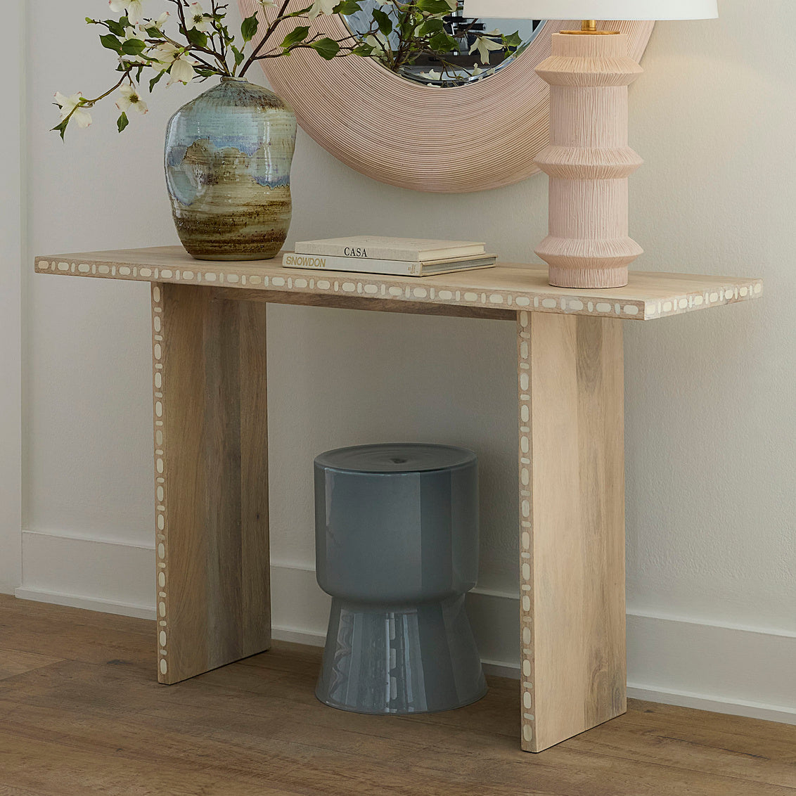 Wooden console table with decorative items against a neutral wall.